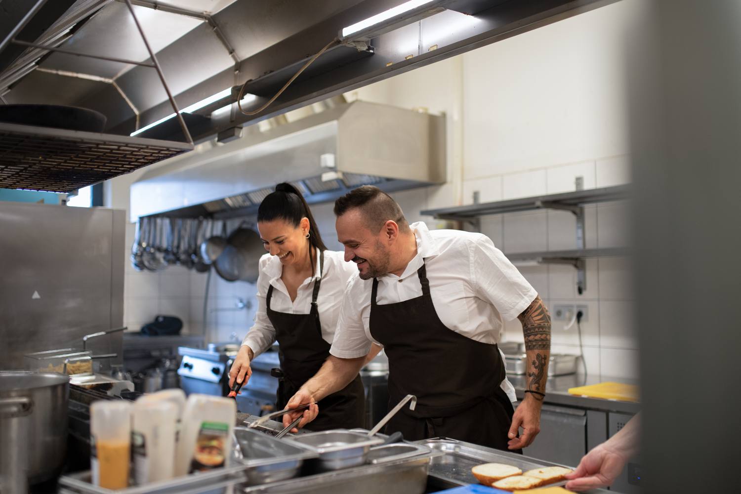 Twee koks aan het werk in een professionele keuken met afzuigkap